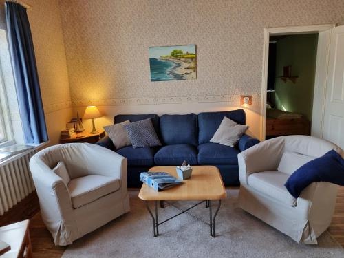 a living room with a blue couch and two chairs at Ferienhof Bisdorf "Steilküste" in Bisdorf
