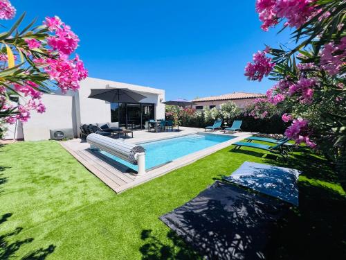une cour arrière avec une piscine et un jardin avec des fleurs roses dans l'établissement Villa KAÏS, à Lecci