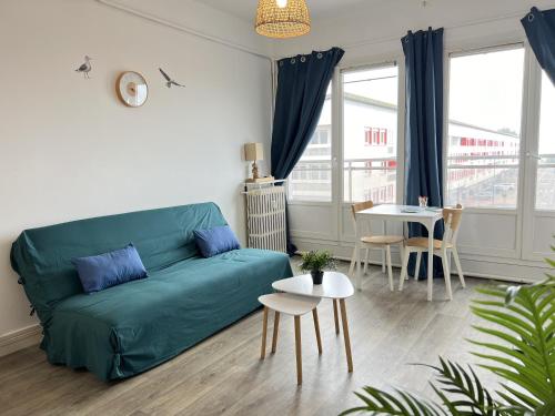 un salon avec un canapé vert et une table dans l'établissement La Mouette, à Calais