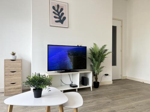 un salon avec une télévision à écran plat sur un mur blanc dans l'établissement La Mouette, à Calais