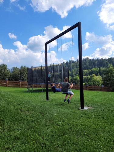 two people playing on a swing set in a field at Luxdomki in Szczawnica