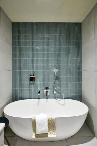 a bath tub in a bathroom with green tiles at Cresta Mahalapye Hotel in Mahalapye