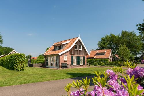 a house with green shutters and purple flowers at The Forest Owl in Hoge-Hexel