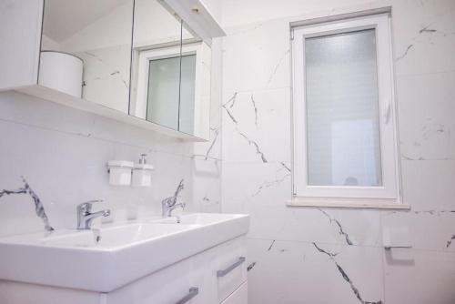 Baño blanco con 2 lavabos y ventana en Villa Joanna - hidden oasis with pool, gym & garrage, en Novalja