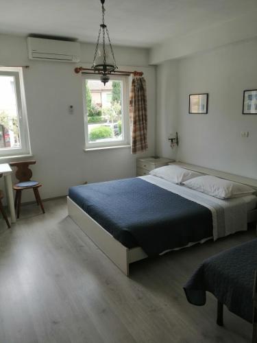 a bedroom with a large bed and two windows at Rooms Izola in Izola