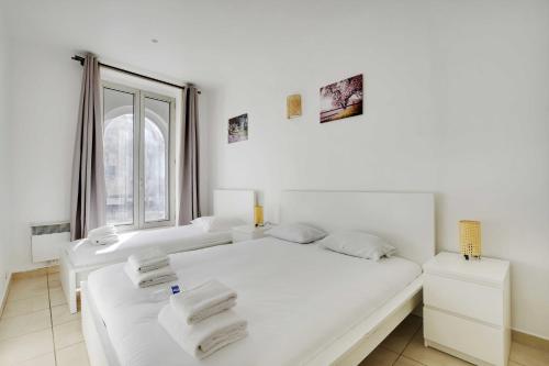 une chambre blanche avec deux lits et une fenêtre dans l'établissement Cozy apartment - 1BR-3P - Gare du Nord, à Paris
