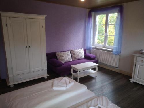 a bedroom with a purple couch and a window at Kräuterbaude in Saupsdorf
