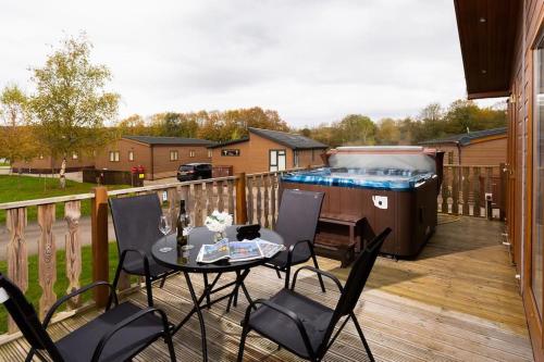 a deck with a table and chairs and a hot tub at Driftwood Lodge - South Lakeland Leisure Village in Carnforth