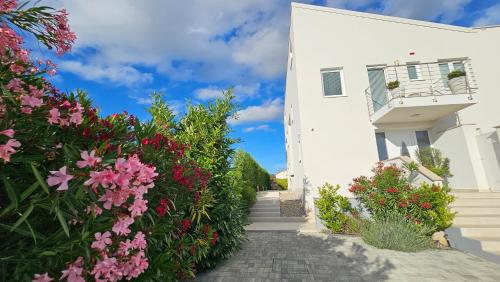 a white house with pink flowers in front of it at Apartments with Pool Casa Bianca in Matohanci