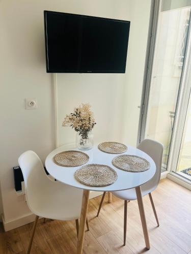 une table à manger blanche avec quatre chaises et une télévision dans l'établissement Appartement Triplex Gare Angers, à Angers