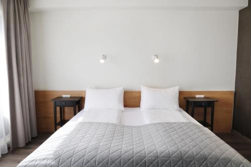 a bedroom with a white bed with two tables at Fosshotel Nupar in Kálfafell