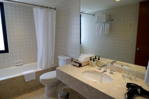a bathroom with a sink and a toilet and a tub at Chatrium Sathon Bangkok in Bangkok