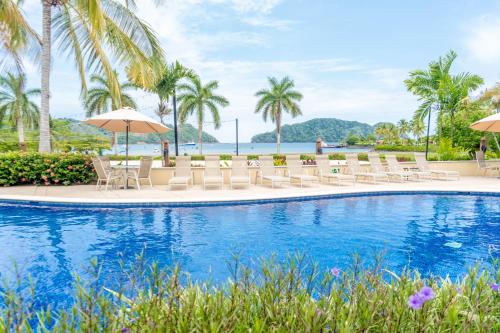 a pool at the resort with chairs and umbrellas at Secluded Garden Paradise Condo @Los Sueños in Herradura