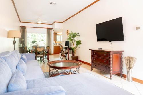 a living room with a blue couch and a flat screen tv at Secluded Garden Paradise Condo @Los Sueños in Herradura
