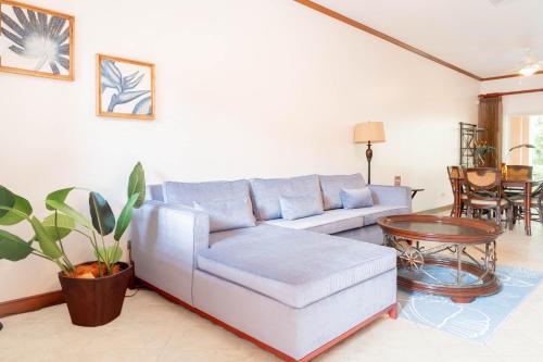a living room with a blue couch and a table at Secluded Garden Paradise Condo @Los Sueños in Herradura