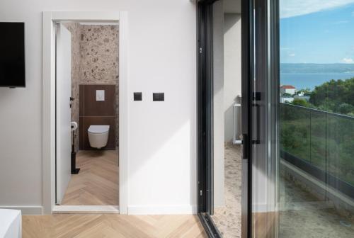 a bathroom with a toilet and a large window at Luxury Villa David's - two heated pool in Podstrana