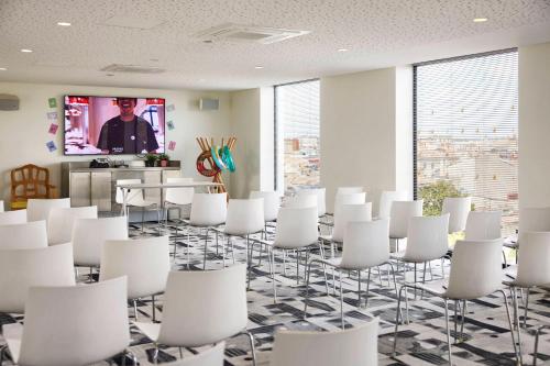 a conference room with white chairs and a tv at Mama Shelter Bordeaux Centre in Bordeaux