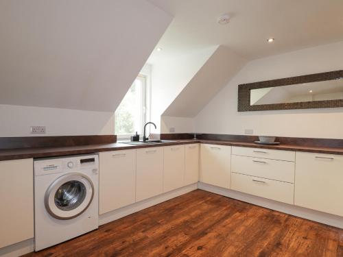 a kitchen with white cabinets and a washer and dryer at Apartment in Foyers in Inverness