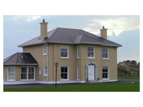 a large yellow house with a black roof at Ambrose Mews B&B in Duncormick