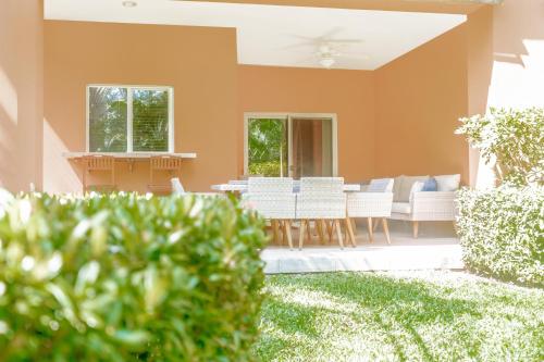 a patio with white chairs and a table at Secluded Garden Paradise Condo @Los Sueños in Herradura