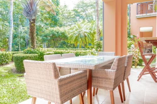 a dining room with a glass table and chairs at Secluded Garden Paradise Condo @Los Sueños in Herradura