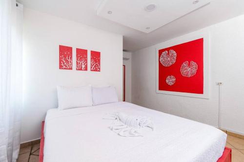 a bedroom with a white bed with red paintings at Casamares Oasis Vacacional con Piscina y Barbacoa in Cabo Rojo
