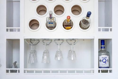a white cabinet with wine glasses and bottles at Casamares Oasis Vacacional con Piscina y Barbacoa in Cabo Rojo