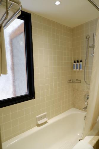 a bathroom with a bath tub with a window at Chatrium Sathon Bangkok in Bangkok
