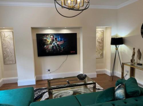 a living room with a couch and a tv on the wall at Glasgow Central Paradise - Spacious 3- Bed House in Glasgow
