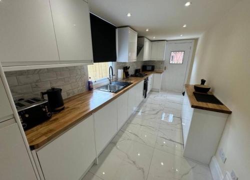 a kitchen with white cabinets and wooden counter tops at Glasgow Central Paradise - Spacious 3- Bed House in Glasgow