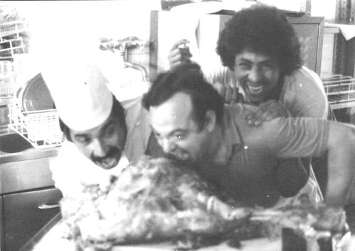 a group of three men sitting around a table with a pizza at Hotel Acapulco in Forte dei Marmi