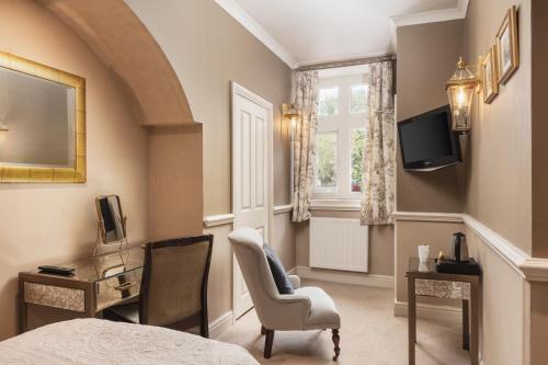 a bedroom with a bed and a chair and a television at Lumley Castle Hotel in Chester-le-Street