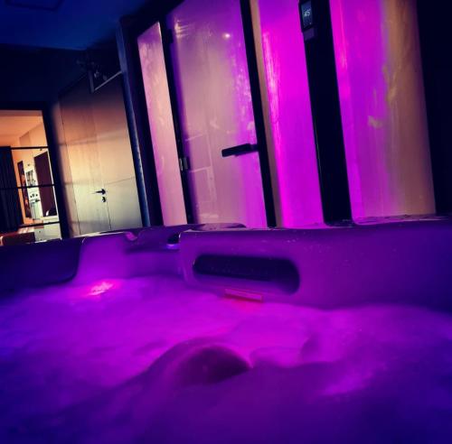 a purple room with a bed with pink lights at Ma nuit ô spA in Reims
