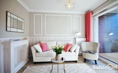 a living room with a white couch and a vase of flowers at Apartamenty BalticON Nadmorskie Tarasy in Kołobrzeg