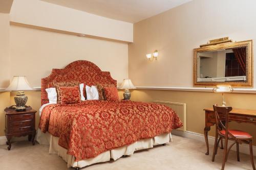 a bedroom with a red bed and a desk and a mirror at Lumley Castle Hotel in Chester-le-Street