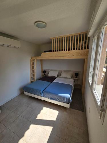 - une chambre avec des lits superposés et un couvre-lit bleu dans l'établissement Villa 7 personnes résidence Mélody, à Santa-Maria-Poggio