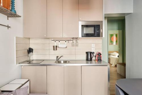 une cuisine blanche avec un évier et un micro-ondes dans l'établissement Élégance Urbaine - 2 chambres, à Paris