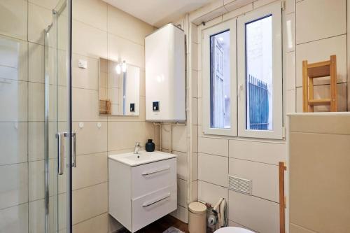 une salle de bain blanche avec un lavabo et une douche dans l'établissement Élégance Urbaine - 2 chambres, à Paris