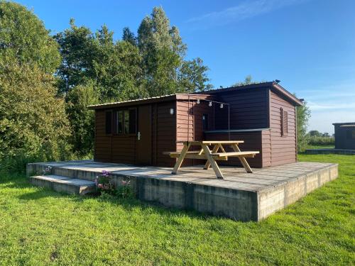 a cabin with a picnic table and a wooden deck at De Meerkoet in Nieuwe-Niedorp