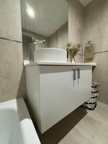 ein weißes Badezimmer mit Waschbecken und Badewanne in der Unterkunft Loft Distrito SMT-YB in San Miguel de Tucumán