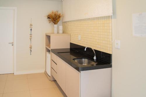 a kitchen with a sink and black counter top at Porto das Dunas Boutique Praia Hotel in Aquiraz