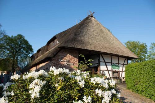 a small building with a thatched roof with flowers at Superior Doppelzimmer 1-2 Personen in Bastorf