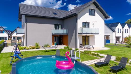 a house with a swimming pool and a pink swan in the yard at Apartamenty Sea Colors - Basen i Sauna! Blisko Plaży - Bardzo Wysoki Standard in Jastrzębia Góra