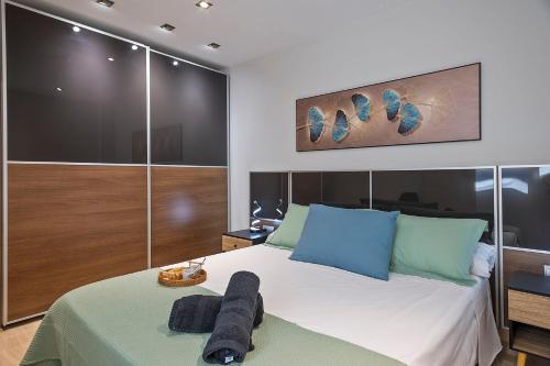 a bedroom with a bed with blue and green pillows at Cómodo y luminoso apto cerca de Playas y Valencia in Sueca