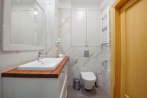 a white bathroom with a sink and a toilet at Apartamenty Akwamaryn in Ustka