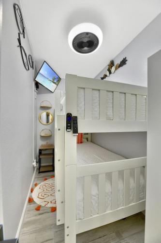 a childs room with white bunk beds and a tv at Stay Awhile Condo Minutes to Beach with Pool in Galveston