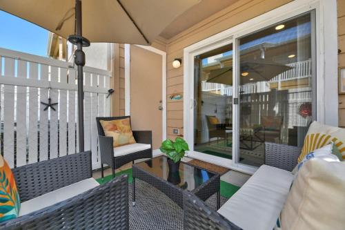 a screened porch with chairs and an umbrella at Stay Awhile Condo Minutes to Beach with Pool in Galveston