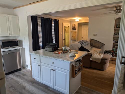 a kitchen with white cabinets and a living room at Landry's Laire in Crescent