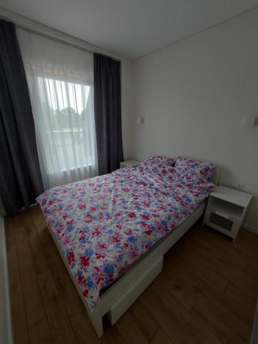 a bedroom with a bed with a floral bedspread at 2 kambarių butas ramioje vietoje in Palanga