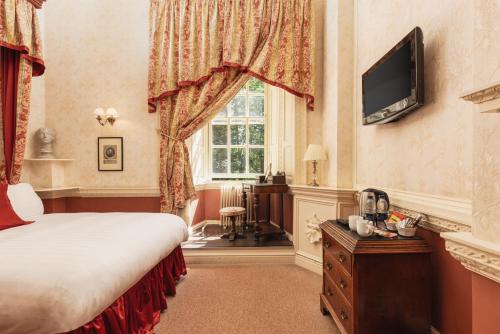 a bedroom with a bed and a tv and a window at Lumley Castle Hotel in Chester-le-Street